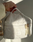 White lace handbag held by a hand with a blurred background