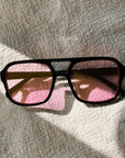 Sunglasses with pink lenses on a textured surface